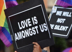 Picture of a POC holding a "Love is amongst us" poster in crowd.